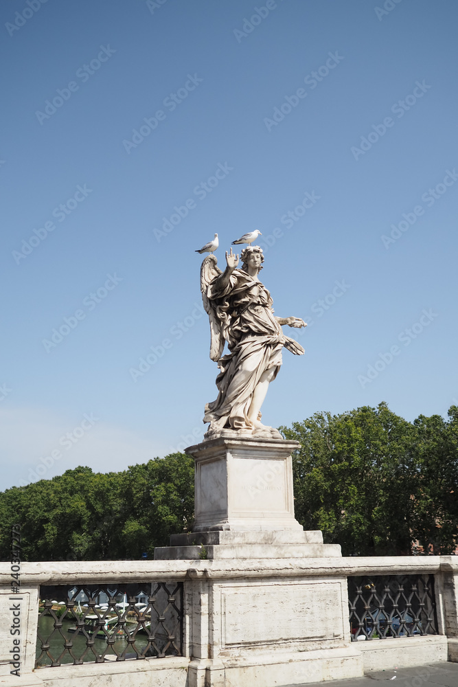 Marble statue by Bernini on the Bridge of Angels, Rome, Italy, with two seagulls sitting on its head