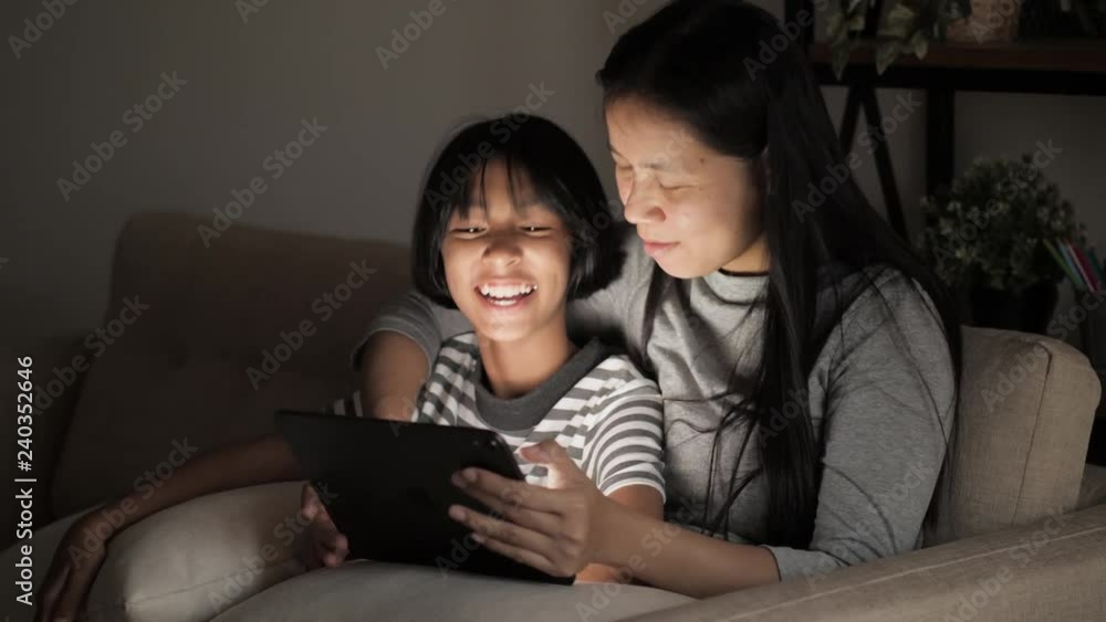 Asian girl and mother using tablet on sofa. Asian girl and mother using tablet on sofa.