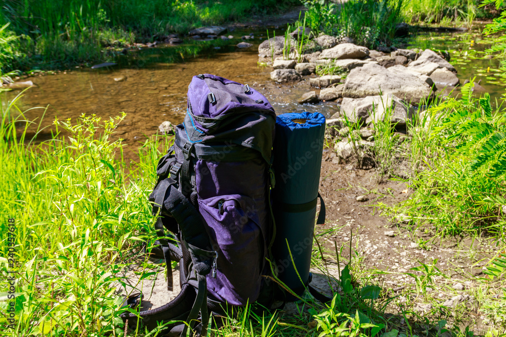 Tourist backpack near a river at summer. Hike concept Tourist backpack near a river at summer. Hike concept