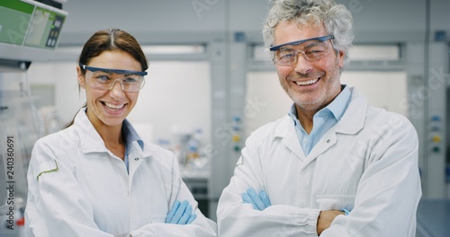 Portrait of two smiling scientists wearing protection glasses satisfied with a great results of completed research in laboratory. Concept: research,biochemistry, pharmaceutical medicine