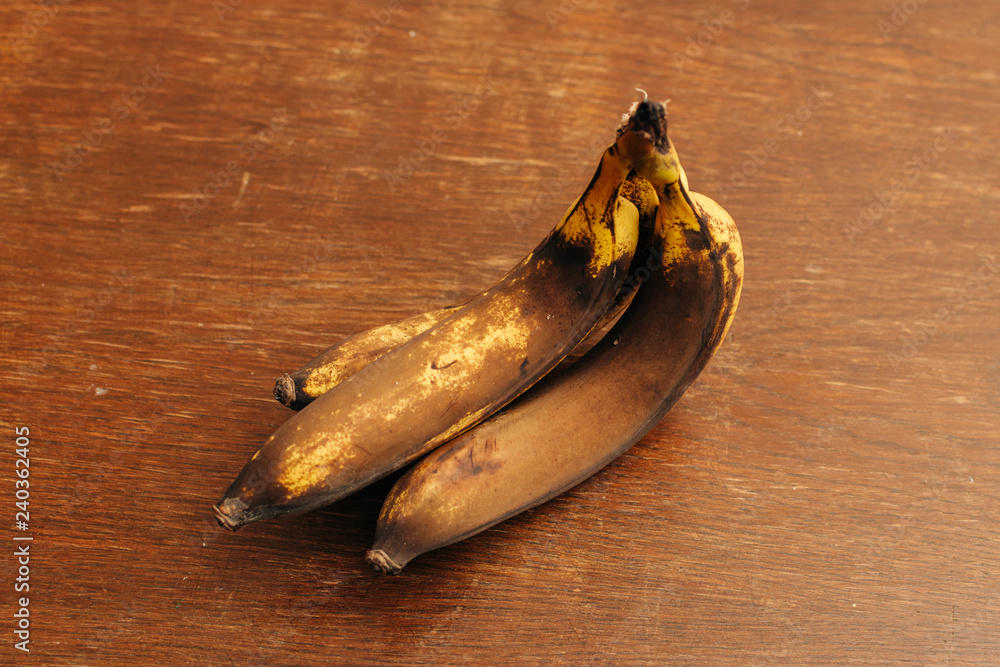 Fototapeta premium 3 rotten and spoiled brown bananas on wooden background