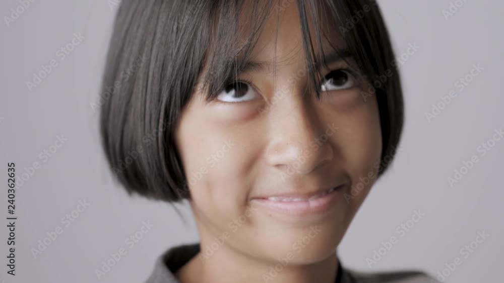 Asian girl show a slow smile on gray background.. Asian girl show a slow smile on gray background..