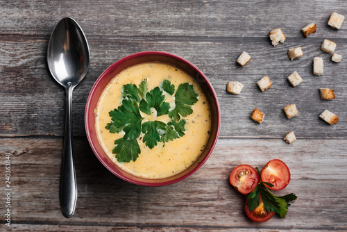 Vegetable pumpkin cream soup with parsley in a bowl and a spoon