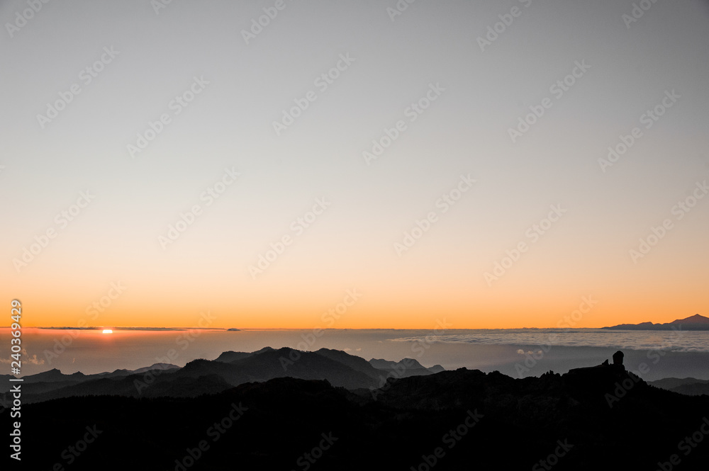 GRAN CANARIA, SPAIN - NOVEMBER 6, 2018: Beautiful sunrise view from Roque Nublo mountain among thick clouds and bright sun light