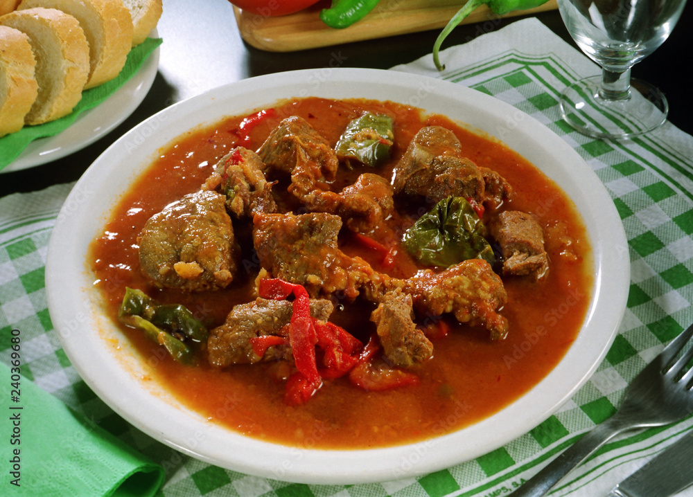 Plato de carne de ternera asada con pimientos y salsa de tomate.