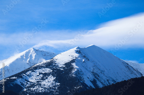 Mountain snow peak  beautiful natural winter backdrop. Ice top of the hill  blue sky background. Alpine landscape.