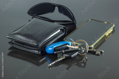 wallet, sunglasses keys and phone isolated on black 
