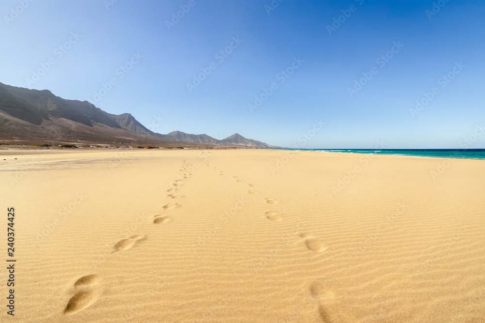 Fuerteventura, Canary Islands, Spain. Cofete beach with endless horizon and traces on sand. Volcanic hills in the background and Atlantic Ocean. Fuerteventura, Canary Islands, Spain. Cofete beach with endless horizon and traces on sand. Volcanic hills in the background and Atlantic Ocean.