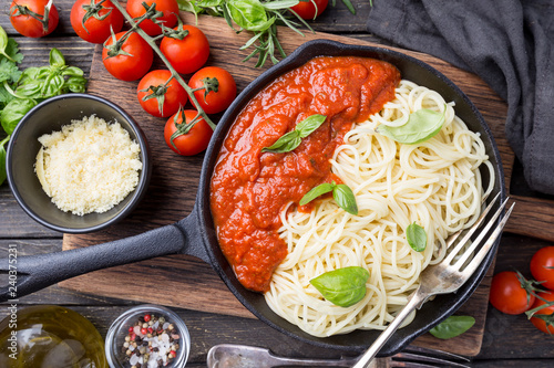 Spaghetti pasta with tomato sauce and basil over wooden background, top view