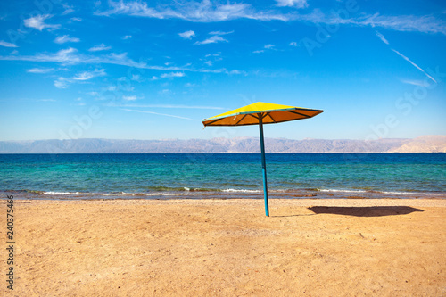 Beach on the shore of the Red Sea. Umbrella, water and beach. Resort in the Aqaba, Jordan near Israel Ejlat.