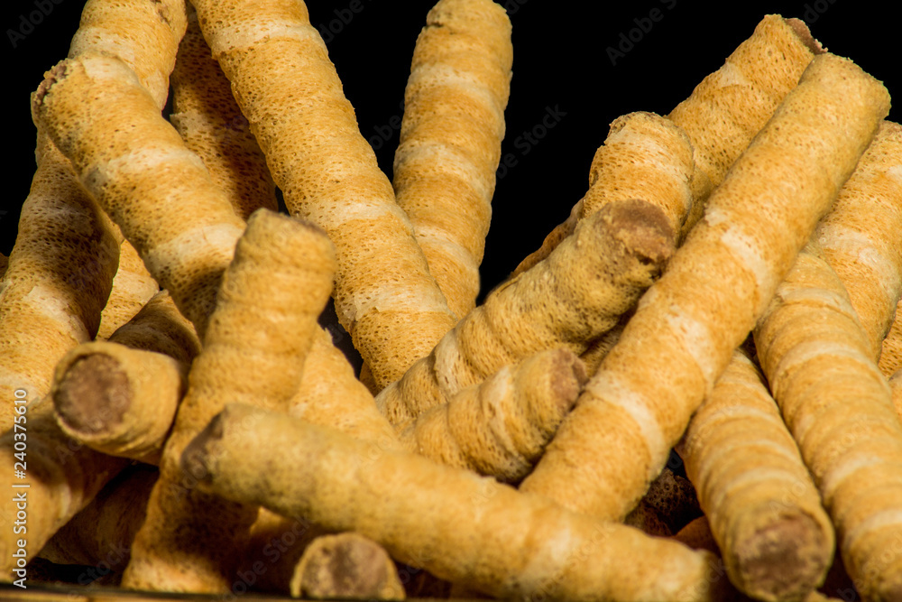 wafer tubes with chocolate filling photographed close-up on a black background wafer tubes with chocolate filling photographed close-up on a black background