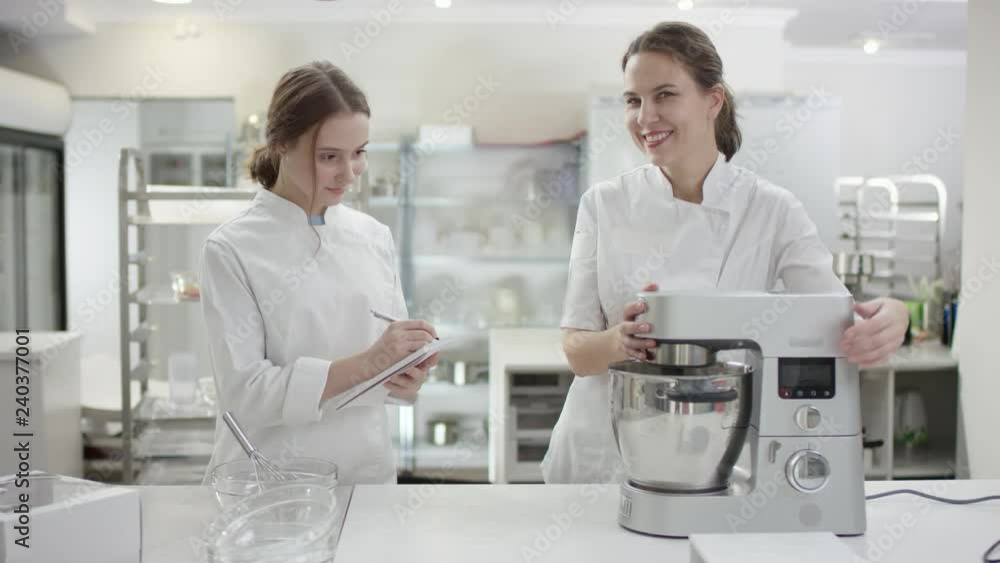 Chef teaching young cook to prepare dish and to use kitchen machines. Chef teaching young cook to prepare dish and to use kitchen machines.