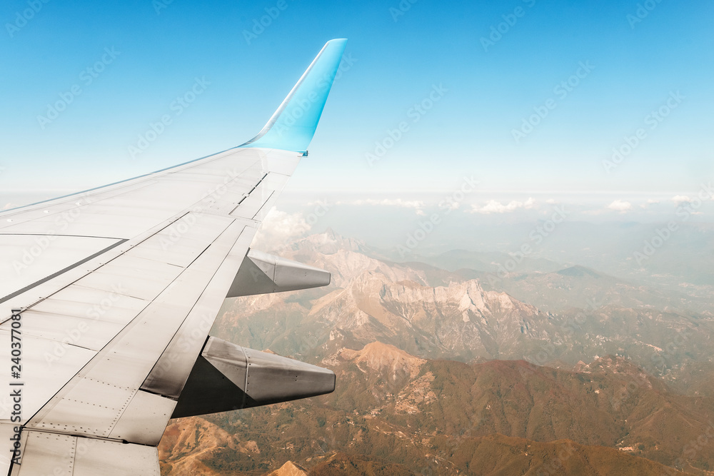 view from the airplane porthole to the mountain peaks with a wing