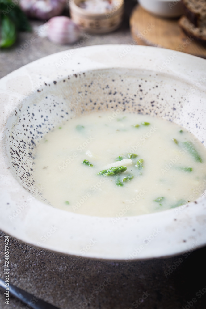 Fresh asparagus cream soup in a bowl over gray stone table Fresh asparagus cream soup in a bowl over gray stone table