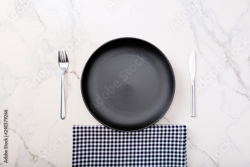 Black plate on marble countertop with black plaid napkin