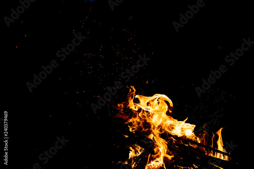 Burning woods with firesparks, flame and smoke. Strange weird odd elemental fiery figures on black background. Coal and ash. Abstract shapes at night. Bonfire outdoor on nature. Strenght of element. photo