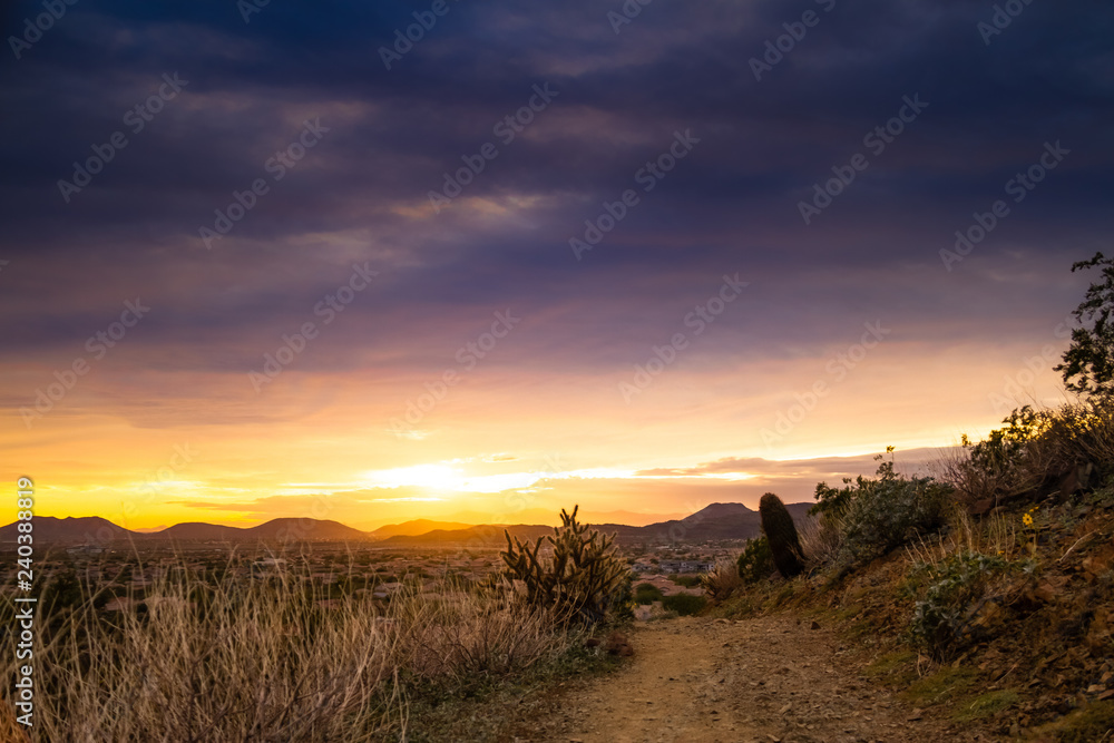 A trail through the desert of the American southwest in Arizona looking at a colorful sunset with clouds.