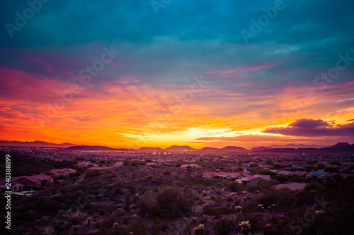 A colorful sunset over a neighborhood in the desert of the American southwest. The sky has warm golden colors on the horizon with cool blue tones in the clouds at the top of the image. © Jason Yoder