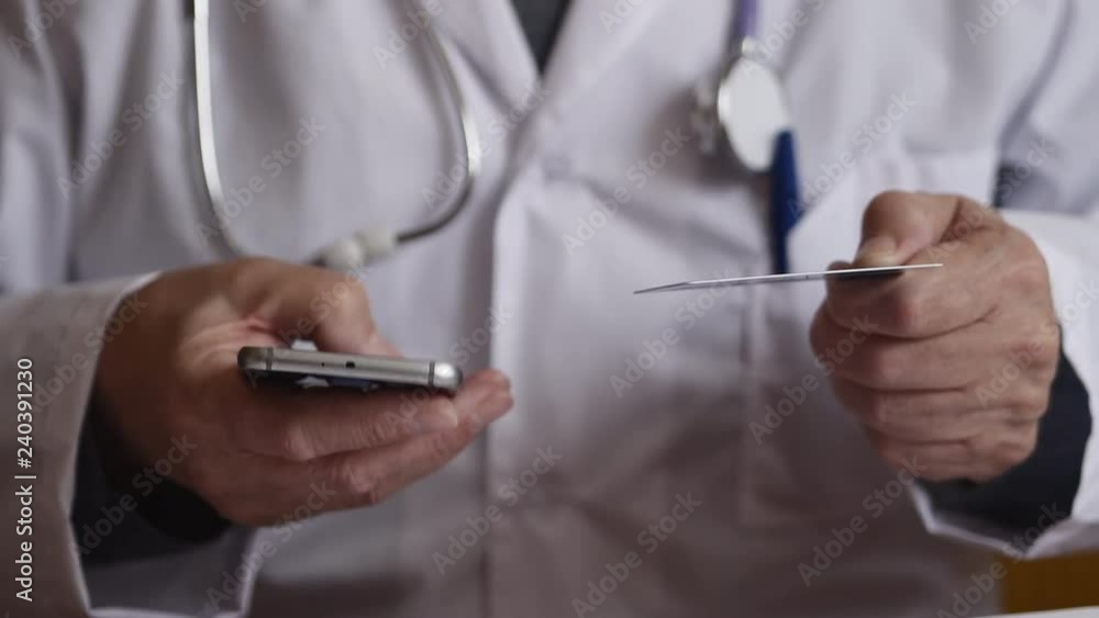 Doctor Using Mobile Phone With Credit Card Doctor Using Mobile Phone With Credit Card