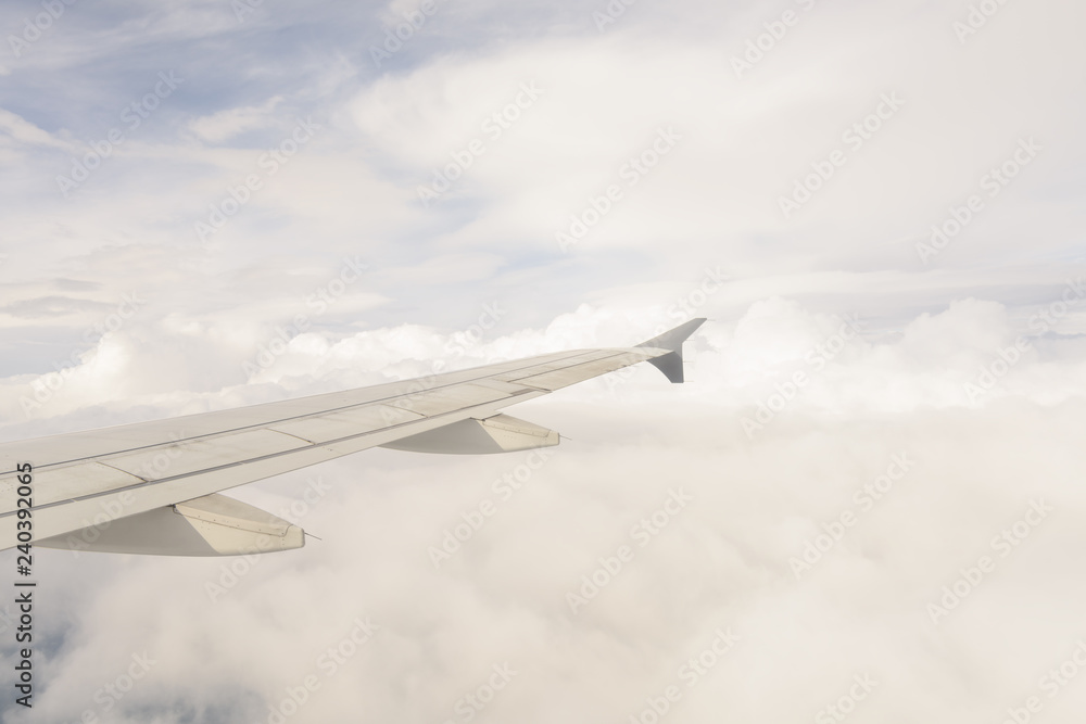 View of the wing of an airplane with blue sky and white clouds background View of the wing of an airplane with blue sky and white clouds background