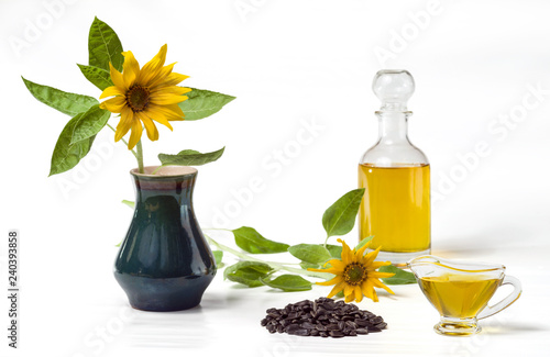 Fototapeta Naklejka Na Ścianę i Meble -  Sunflower oil in a glass decanter and a glass gravy boat, a bunch of sunflower seeds and a sunflower in a vase isolated on a white background. Selective focus.