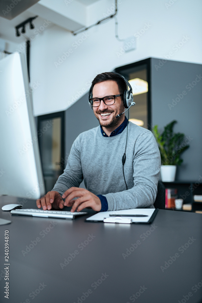 © bnenin - Happy support center worker working on his computer. © bnenin - Happy support center worker working on his computer.