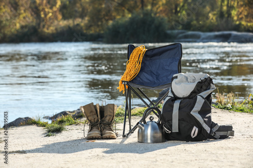 Set of camping equipment on sand near pond