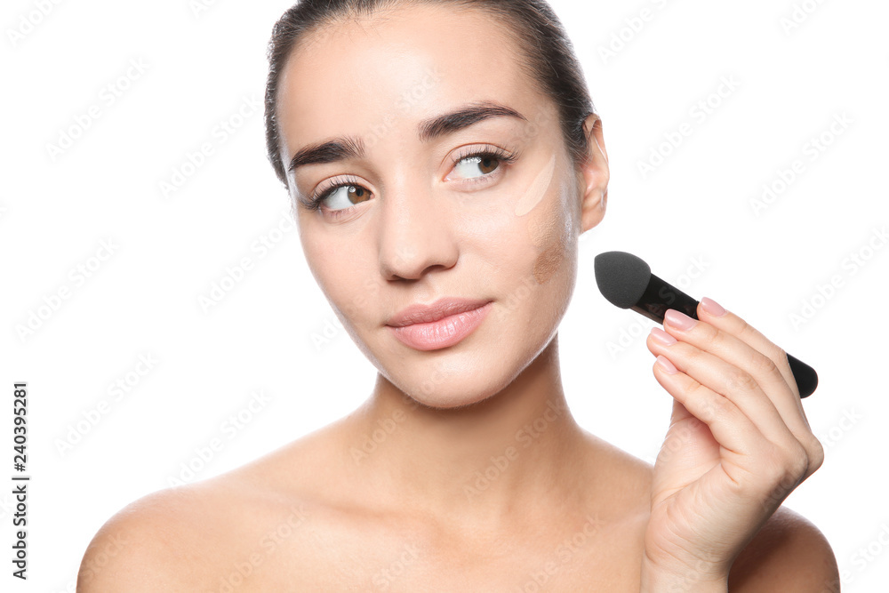 Young woman applying foundation on her face against white background Young woman applying foundation on her face against white background