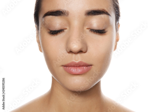 Portrait of young woman with foundation on her face against white background