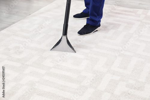 Man removing dirt from carpet with vacuum cleaner indoors, closeup. Space for text