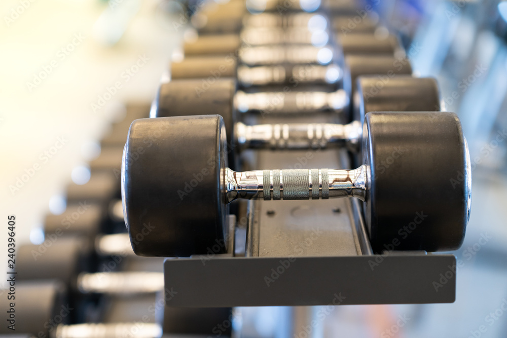 Naklejka premium Closeup rows of metal dumbbells on rack in the gym
