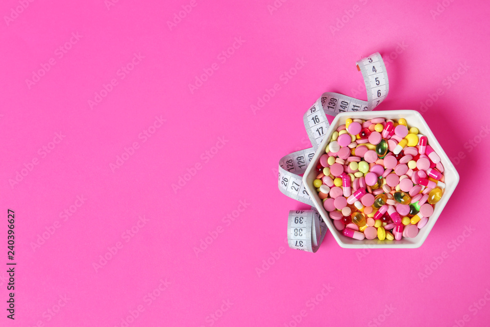 Bowl with weight loss pills and measuring tape on color background, top view. Space for text Bowl with weight loss pills and measuring tape on color background, top view. Space for text