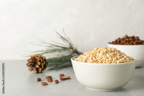 Bowl with pine nuts on table against light background. Space for text