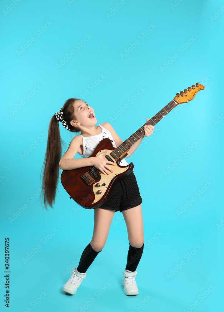 Cute little girl playing guitar on color background