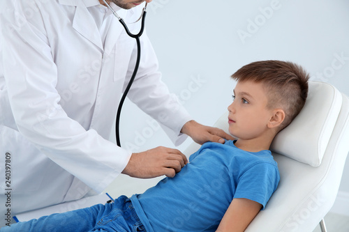 Children s doctor examining patient with stethoscope in hospital