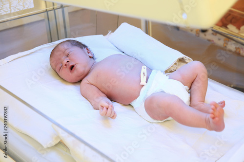 Newborn child under ultraviolet lamps in hospital
