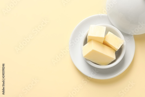 Dish with tasty fresh butter and space for text on color background, top view