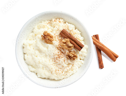 Creamy rice pudding with cinnamon and walnuts in bowl on white background, top view photo