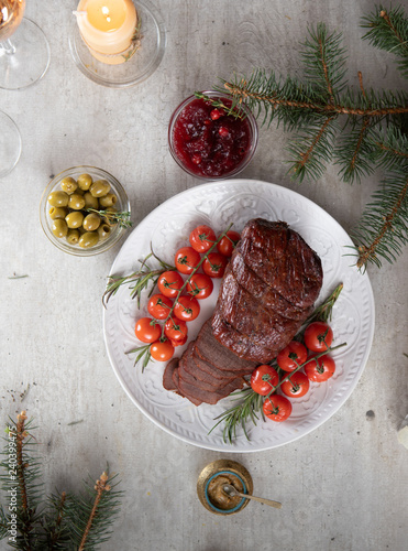 Cooked roast beef sliced with cherry tomatoes and various sauces