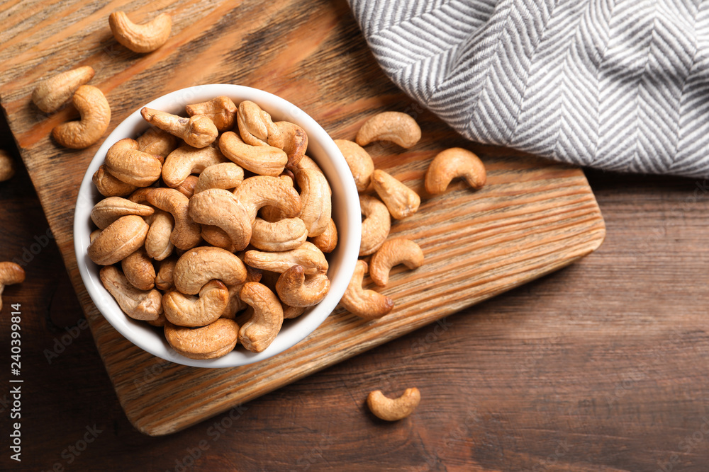 Tasty cashew nuts in bowl on wooden table, top view Tasty cashew nuts in bowl on wooden table, top view