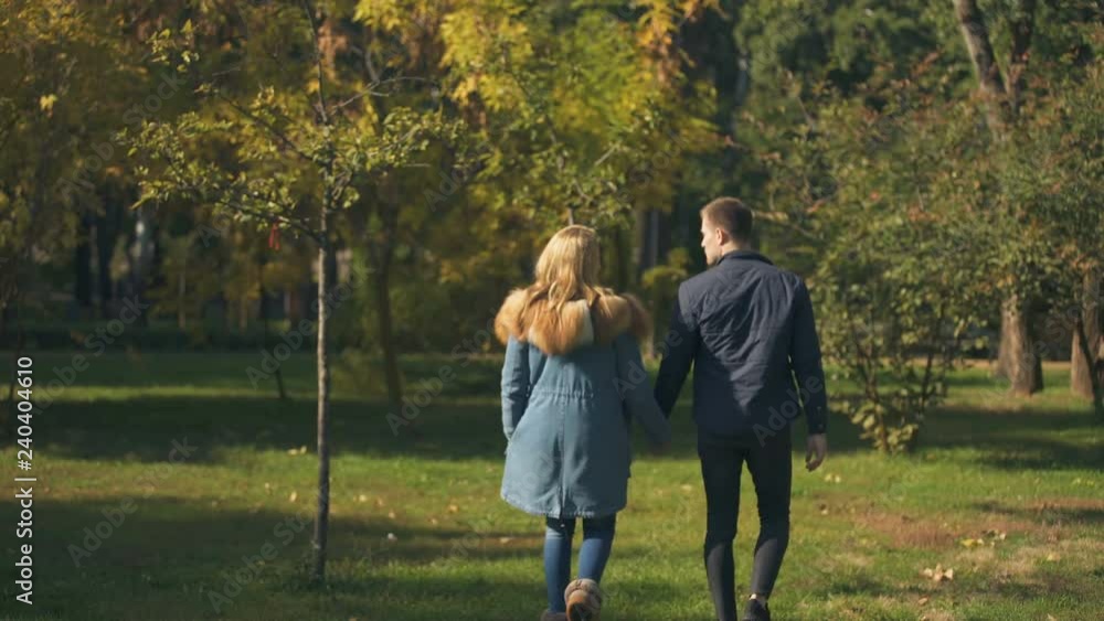 Back view of couple holding hands and walking, bright future, togetherness Back view of couple holding hands and walking, bright future, togetherness