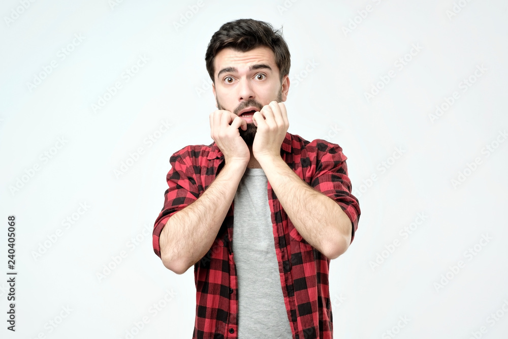 Φωτογραφία Young man covering mouth with hands and round eyes experiencing deep astonishment and fear