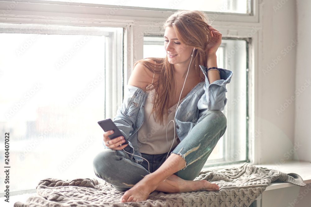Φωτογραφία young beautiful woman enjoying music sitting by the window in her room