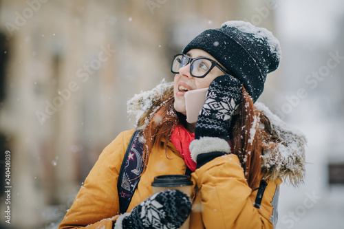 Woman walking in the winter strrt and talking on the mobile phone photo