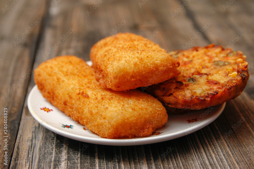 Crispy breaded fried fish fillet and vegetarian burger made from various type of vegetables on old wooden table Crispy breaded fried fish fillet and vegetarian burger made from various type of vegetables on old wooden table