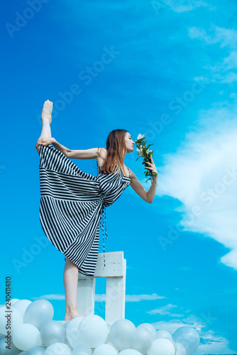 Fashion portrait of woman. girl with flowers sit in sky. feeling freedom and dreaming. inspiration and imagination. woman in summer dress with party balloons. acrobatics and sport. spli photo