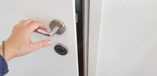 white door opening girl's hand on metla door handle photo