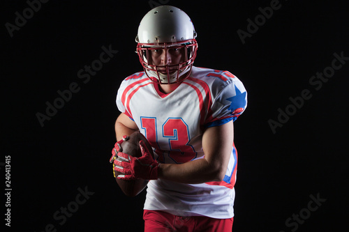 American football player wearing helmet ready to throw ball on black background