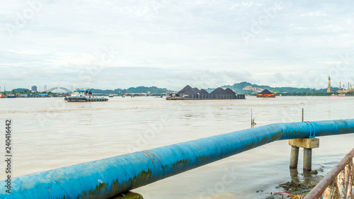 boat pull barge full of coal cruising Mahakam River in front of Samarinda  Great Mosque photo