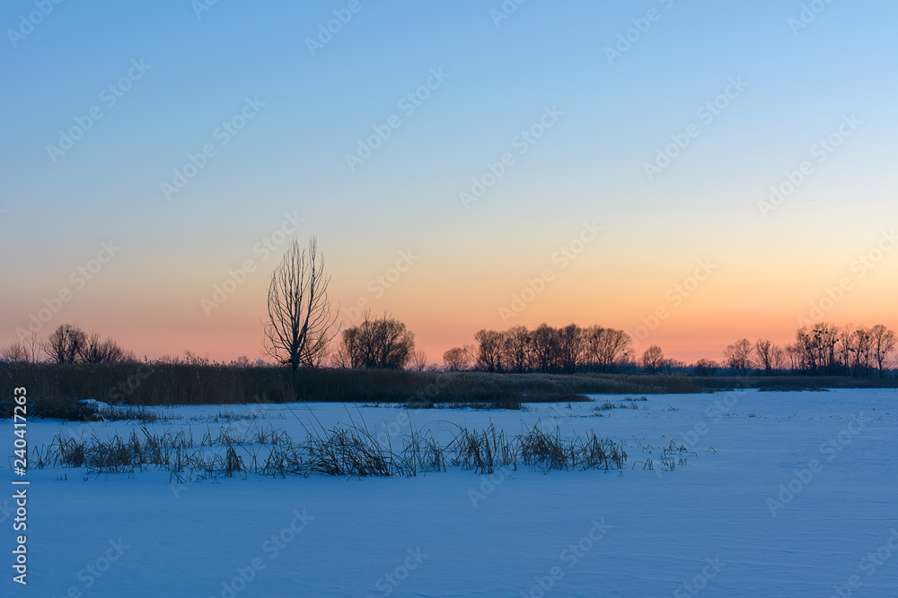Sunset in the winter over the river covered with ice Sunset in the winter over the river covered with ice